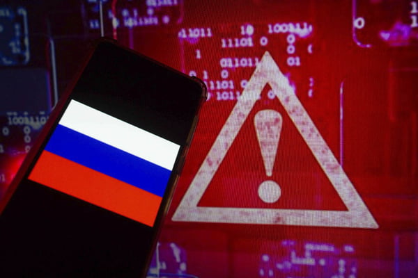 Imagem ilustrativa mostra mão segurando celular com a bandeira da Ucrânia e um fundo com um sinal de alerta vermelho numa tela com números - Metrópoles