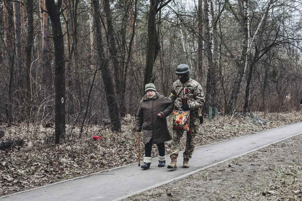 Soldado ucraniano ajuda mulher mais velha a andar até um abrigo antibombas durante invasão russa - Metrópoles