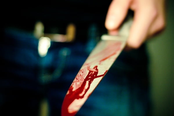 Pessoa segurando uma faca com conteúdo vermelho que lembra sangue - Metrópoles