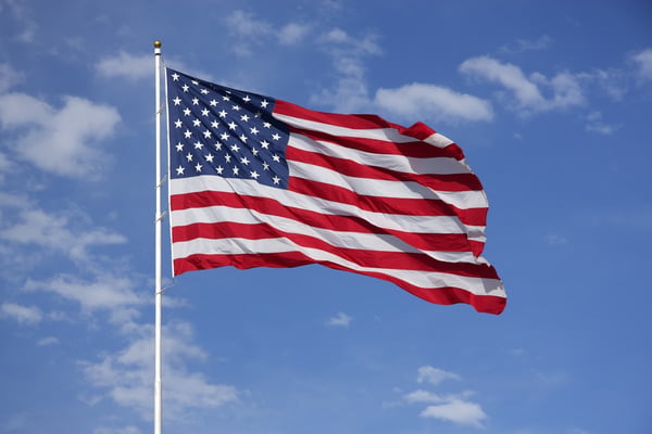 Bandeira dos Estados Unidos flamulando num céu azul celeste - Metrópoles