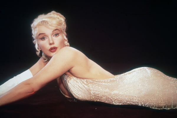Marilyn Monroe deitada usando batom vermelho, em 1960