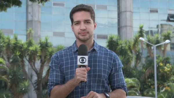 Gabriel Luiz, repórter da TV Globo, segurando microfone