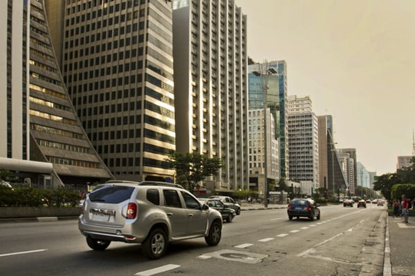 Carros se movimentando em uma rua em frente a prédios- Metrópoles