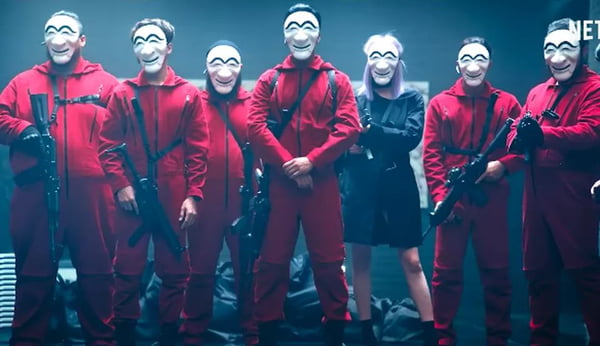 Elenco da versão coreana da série da Netflix "La casa de papel" posam com uniformes vermelhos, máscaras e armas para foto promocional - Metrópoles