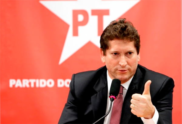Jilmar Tatto, um dos dirigentes da campanha à presidência de Lula, discursa com a mão fazendo sinal de "joia" diante de microfone e com painel do PT ao fundo - Metrópoles