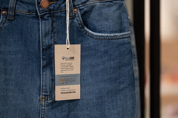 Na imagem com cor, calça jeans com etiqueta