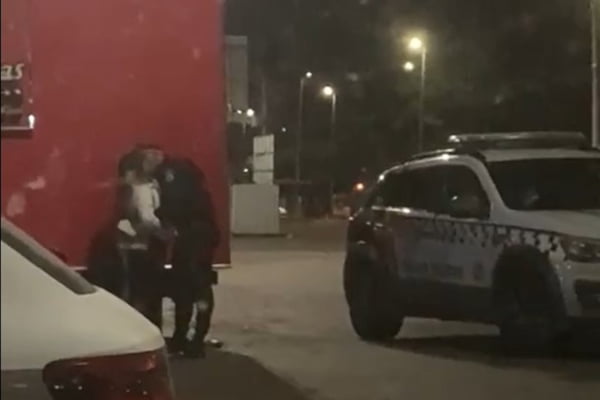 homem de farda se curva para beijar mulher ao lado de viatura