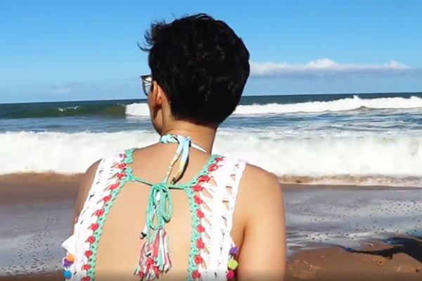 Menina com canga, de costas, olhando para o mar