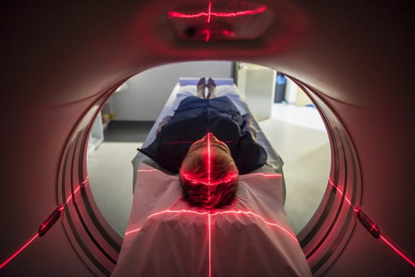 A person lies on a hospital stretcher undergoing a CT scan - Metropolis