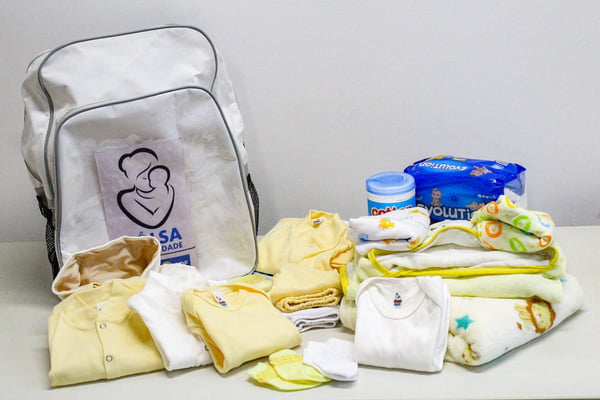 Foto de uma mochila branca com itens para bebês
