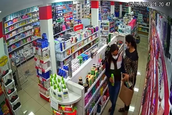 Mulheres em pé ao lado de prateleiras com produtos em farmácia