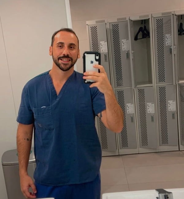Anestesista Giovanni Quintella Bezerra, flagrado estuprando mulher grávida durante parto, tira foto com seu celular em espelho de vestiário em hospital. Ele usa uniforme médico azul marinho - Metrópoles