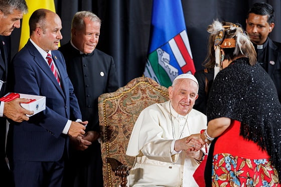 homem religioso sentado em cadeira cumprimenta líder indígena
