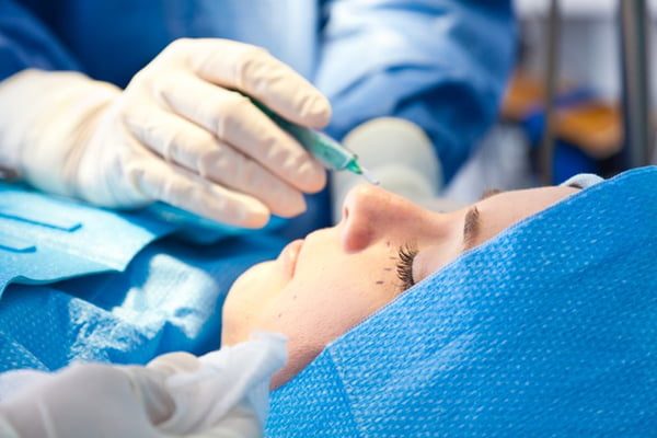 Pessoa deitada em maca hospitalar para fazer cirurgia nos olhos- Metrópoles