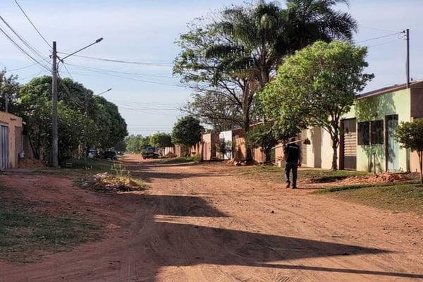 Rua onde idoso foi resgato em condições desumanas no Mato Grosso. Ela tem laterais cercadas por casas simples e o caminho é de terra batida, onde um homem caminha com enxada nas costas - Metrópoles