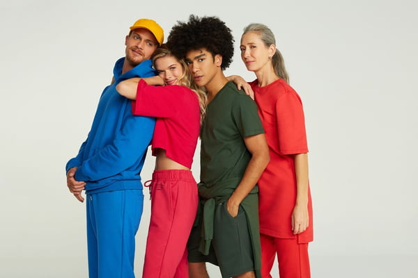 Campanha de divulgação da Simples, submarca da Reserva, onde modelos posam com as roupas em um fundo branco. Na foto, é possível ver quatro modelos usando moletons da marca nas cores azul, amarelo, cinza e vermelho.