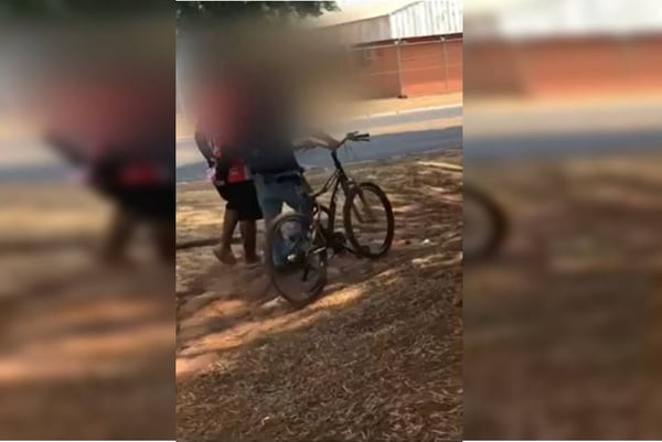 Estudante com síndrome rara é agredido por colega em saída de escola no Gama, Distrito Federal. Na foto, dois alunos próximos a uma bicicleta brigam num campo de terra - Metrópoles