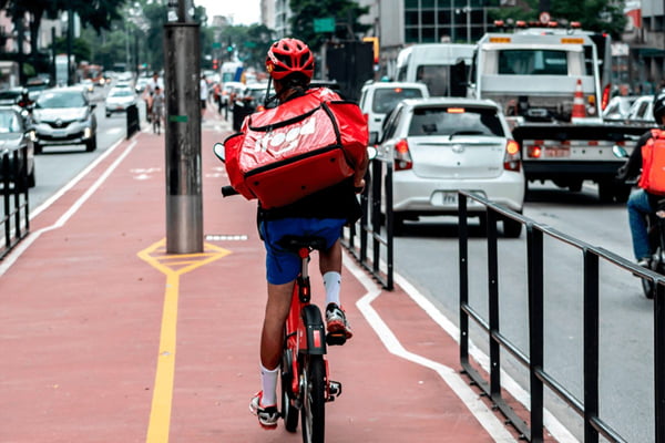 Imagem colorida mostra entregador do iFood andando de bicicleta pela ciclovia da avenida Paulista, em São Paulo - Metrópoles