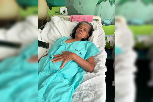 Mulher deitada em cama de hospital com roupa azul