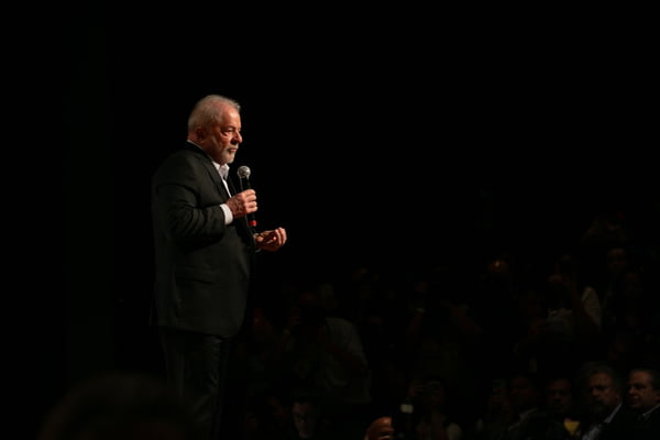 Imagem colorida mostra Luiz Inácio Lula da Silva, presidente eleito, em pé em um palco. Ele usa terno e segura um microfone - Metrópoles