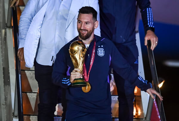 O jogador da seleção argentina Messi com a taça da Copa do Mundo desce de avião após chegar do Catar com o título - Metrópoles
