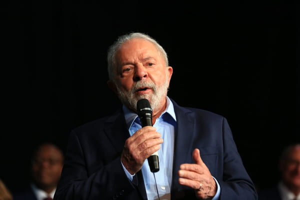 O presidente eleito Lula em coletiva de impresa para anúncio de novos ministros para o próximo governo. Ele fala em púlpito diante de microfone - Metrópoles