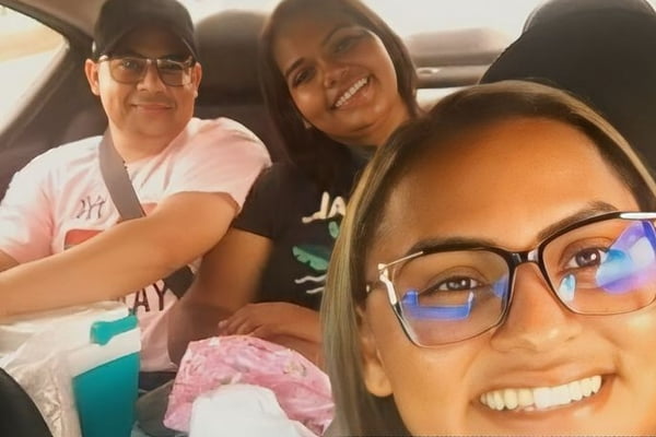 Imagem colorida: mulher de óculos faz selfie no carro com outras duas pessoas sentada no banco de trás - Metrópoles