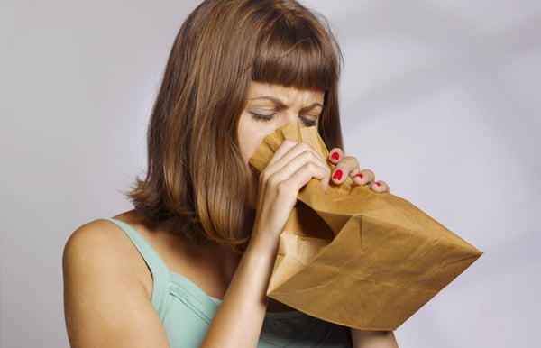 Mulher tentando se acalmar respirando dentro de saco de pão
