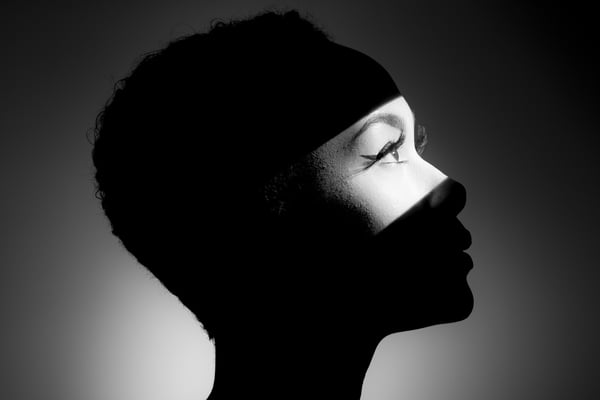 Imagem em preto e branco de mulher no escuro com os olhos na luz - Metrópoles