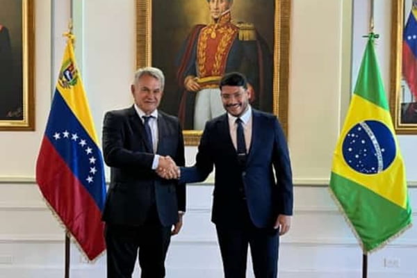 Imagem mostra dois homens apertando as mão próximos às bandeiras do Brasil e da Venezuela, na cerimônia de recepção do novo diplomata - Metrópoles