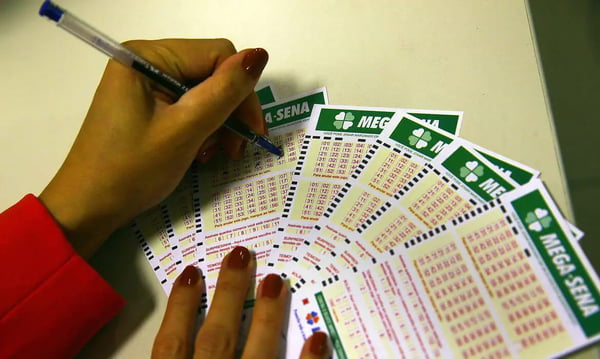 Loterias: imagem colorida mostra mulher preenchendo números em cartelas da Mega-Sena