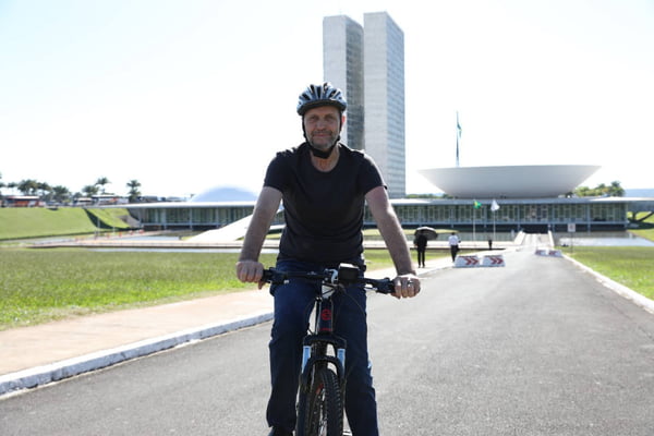 homem de camiseta preta montado em bicicleta em frente ao Congresso Nacional