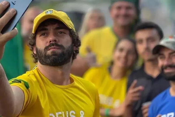 Em foto colorida homem vestindo camisa do Brasil faz selfie com celular preto. O homem é o bolsonarista Esdras Jonatas