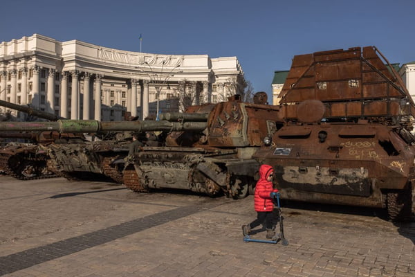 Imagem colorida mostra criança perto de tanques de guerra em Kiev, na Ucrânia