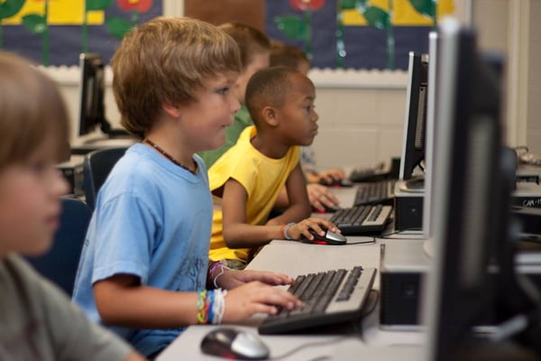 Foto colorida de crianças norte-americanas no computador - Metrópoles
