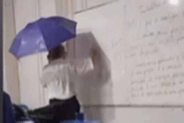Imagem mostra professora usando guarda-chuva enquanto dá aulas em uma escola - Metrópoles