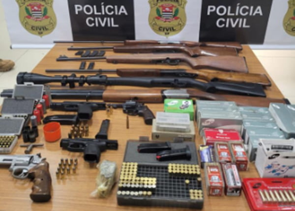 Imagem colorida de armas, cartuchos e dinheiro apreendidos com ladrões em SP
