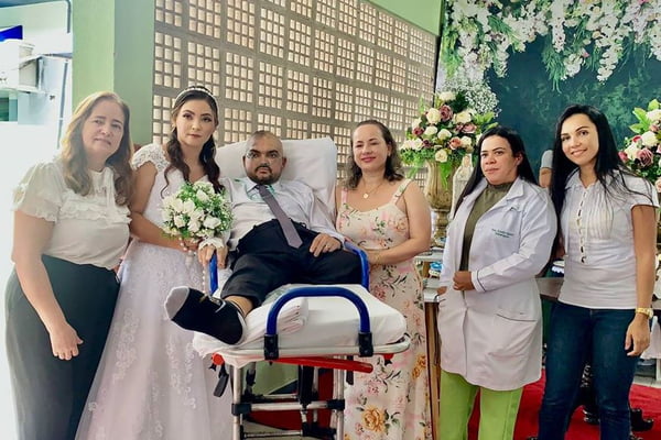 Imagem colorida: paciente com câncer em maca ao lado de noiva e médicas - Metrópoles