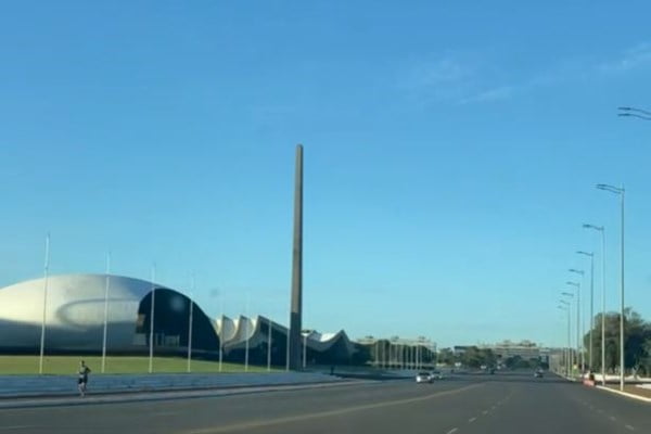 Imagem colorida mostra avenida e monumento ao lado esquerdo