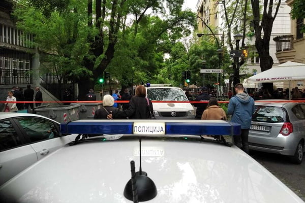 Imagem colorida mostra carro de polícia e pessoas do lado de fora de escola que foi atacada a tiros por adolescente na Sérvia
