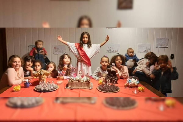 menina vestida de jesus atras de mesa com crianças ao redor - metrópoles
