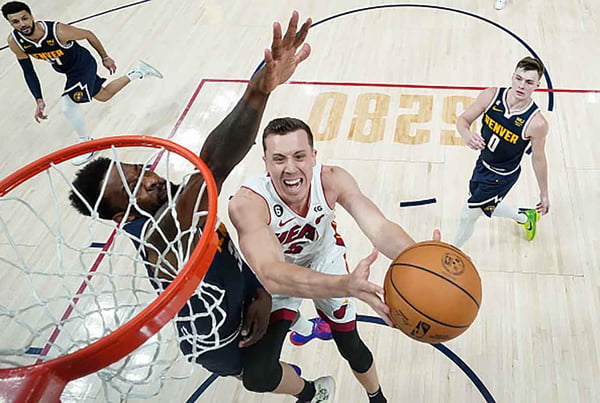 NBA finals: foto colorida de jogador do miami heat na tentiva de cesta e jogador de denver nuggets tenta bloquear