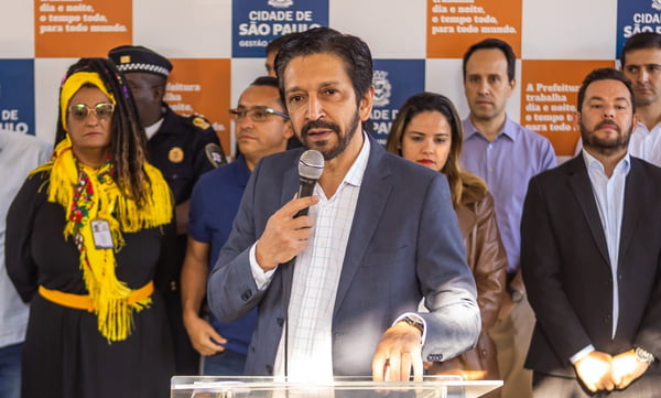 Imagem colorida mostra Ricardo Nunes falando ao microfone em um palanque politico