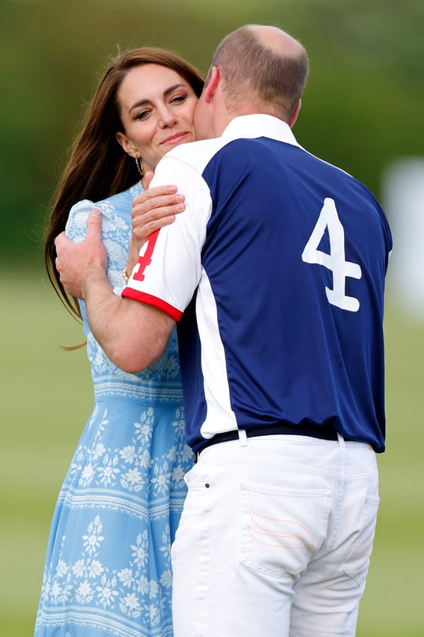 Foto colorida de mulher e homem se abraçando. Ela usa um vestido azul claro e ele roupa esportiva de polo - Metrópoles