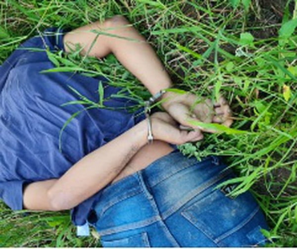 Imagem colorida do corpo de homem algemado e debruçado sobre a grama