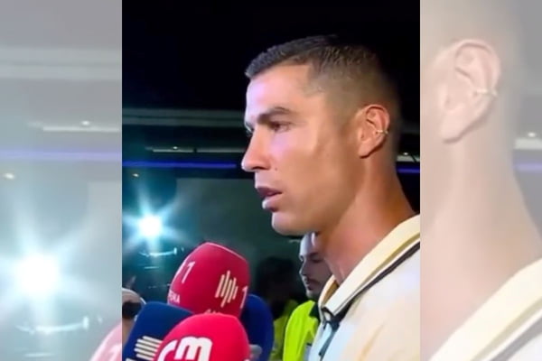 Cristiano Ronaldo visto de lado, diante de microfones de jornalistas