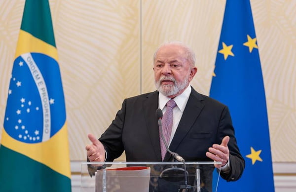 imagem colorida de Lula em entrevista coletiva na Bélgica, com as bandeiras do Brasil e da União Europeia ao fundo - Metrópoles