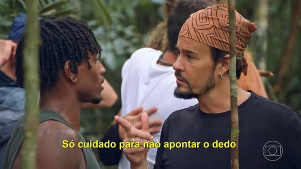 Paulinho Vilhena apontando o dedo para Guilherme em No Limite. O ator usa bandana
