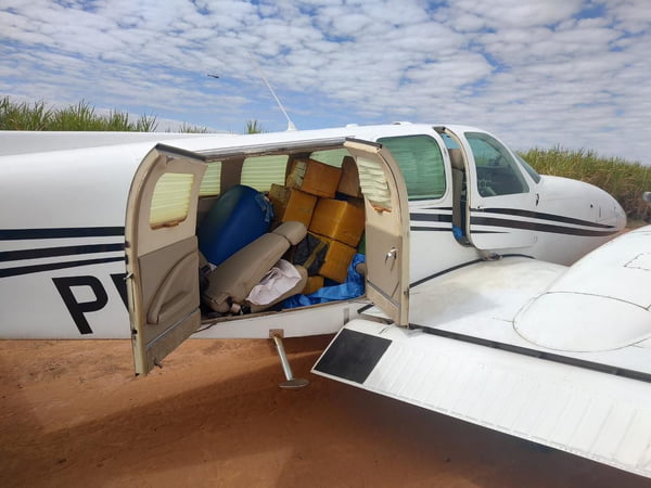 Avião branco com portas abertas e vários pacotes fechados contendo mais de 500 kg de cocaina