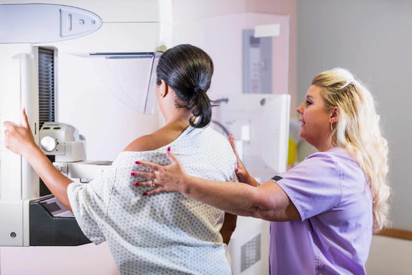 Foto mostra mulher negra fazendo mamografia para detectar câncer de mama
